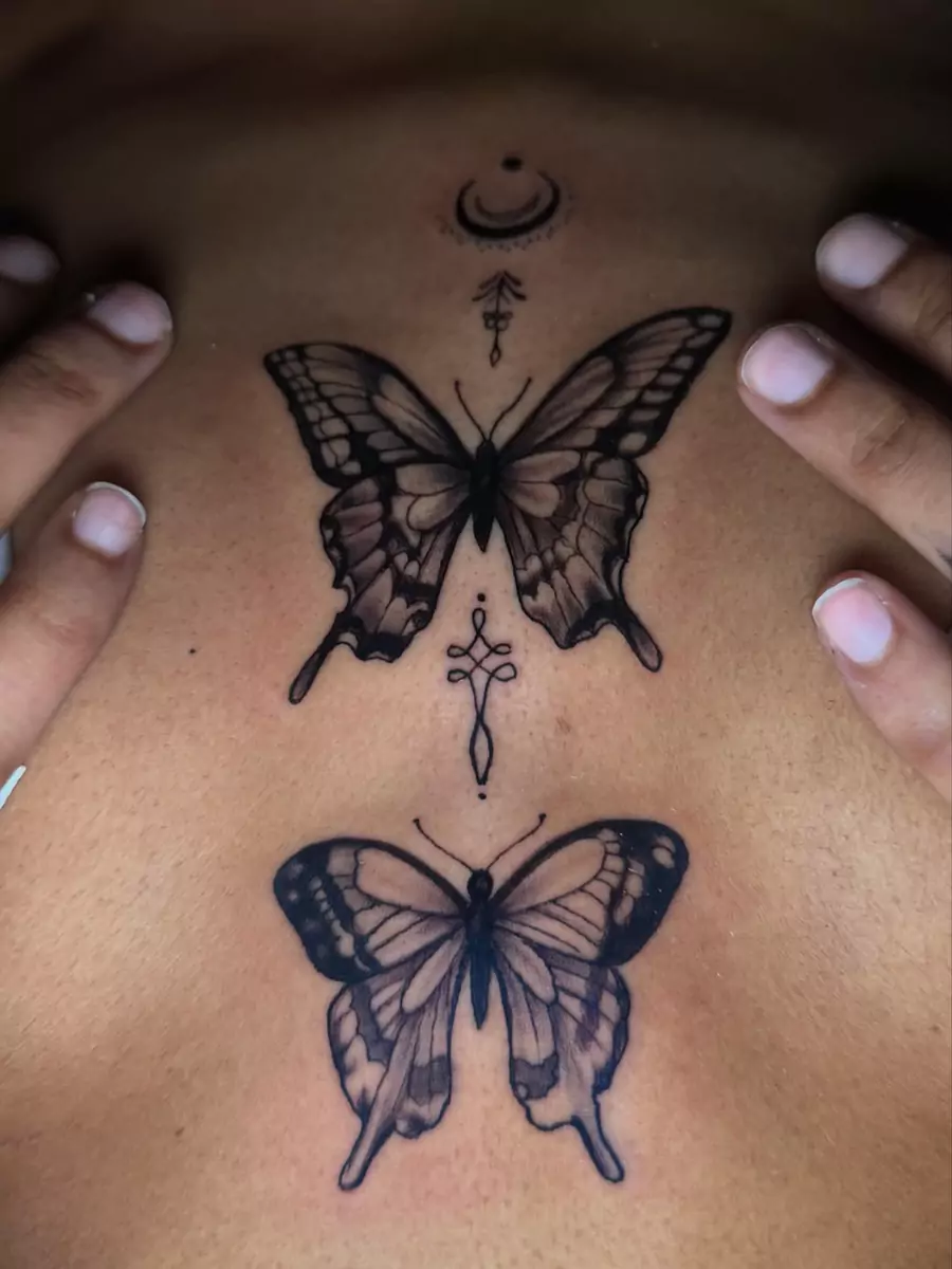 Two black and gray butterflies mirrored down the sternum with a small crescent and star