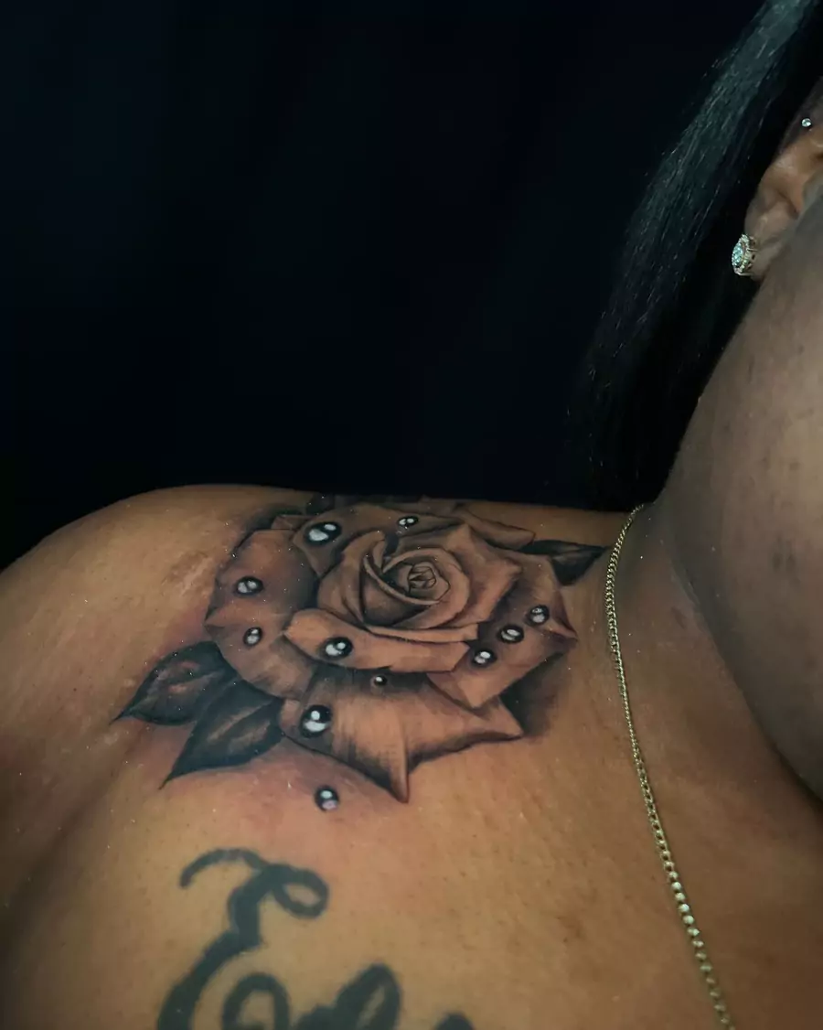 A black and gray rose with inset jewels across the shoulder blade