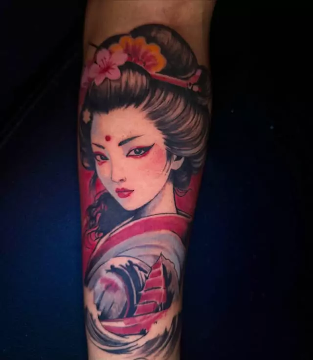 A full color geisha with flowers in her hair on the upper arm