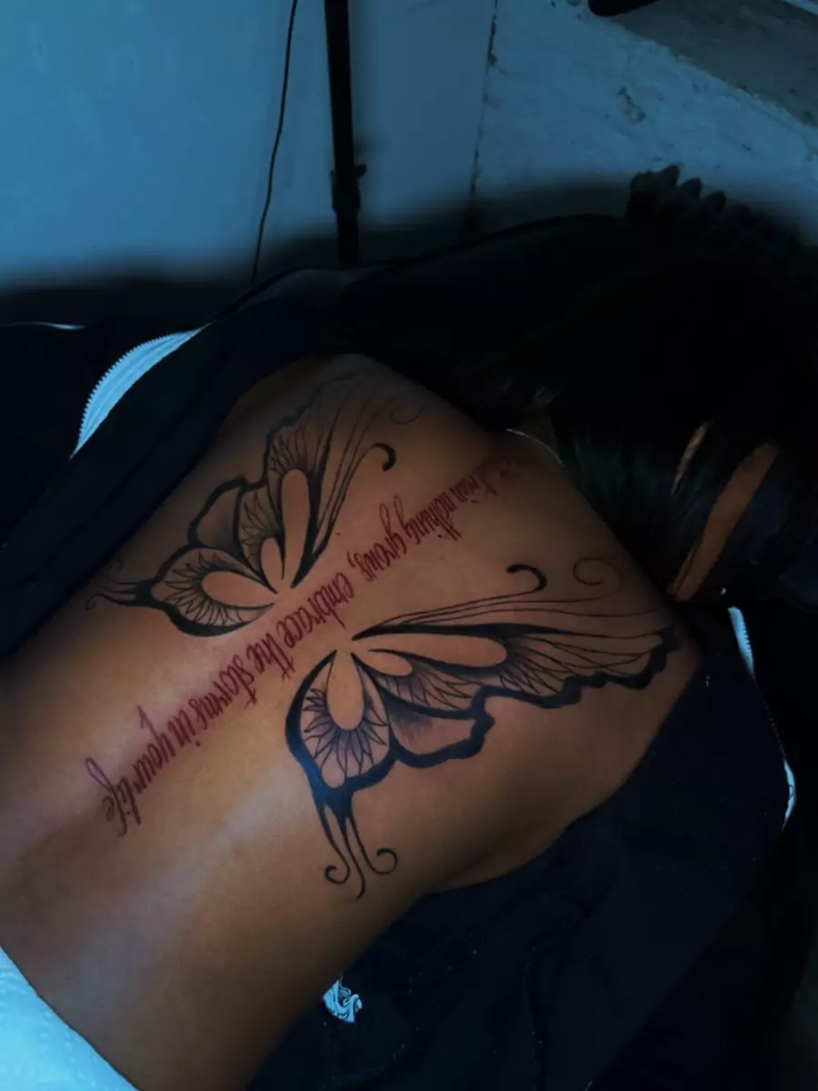 Fine line script and a butterfly running across the shoulder blade