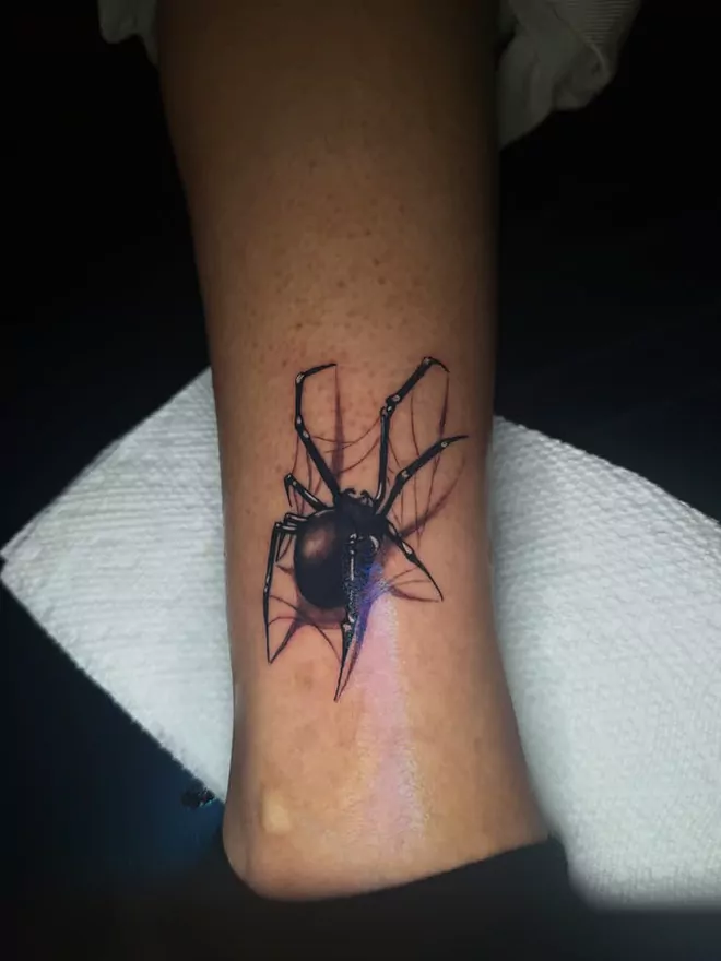 The spider filled in, body solid and legs shaded, the last of the stencil still faintly visible
